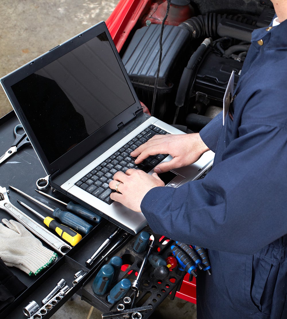 Technician working on laptop with tools nearby