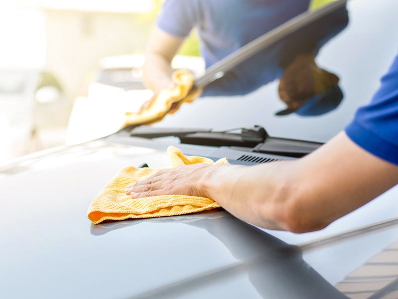 Technician wiping down a car