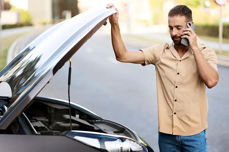 Man on phone near open car hood
